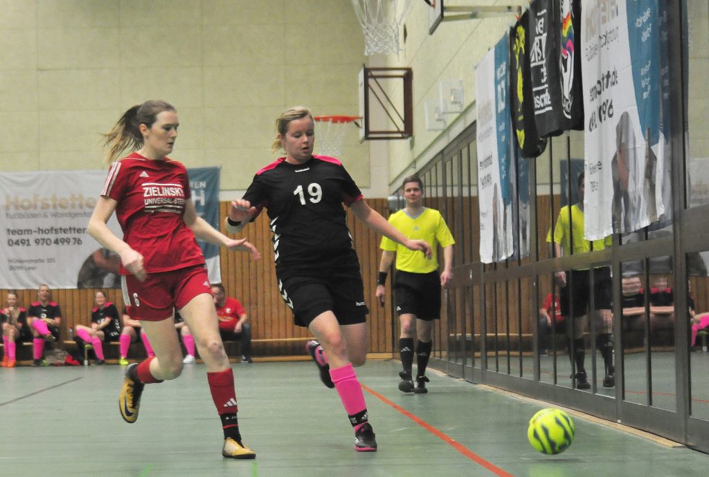 Zwei Fußballspielerinnen und ein Schiedsrichter während des Spiels.