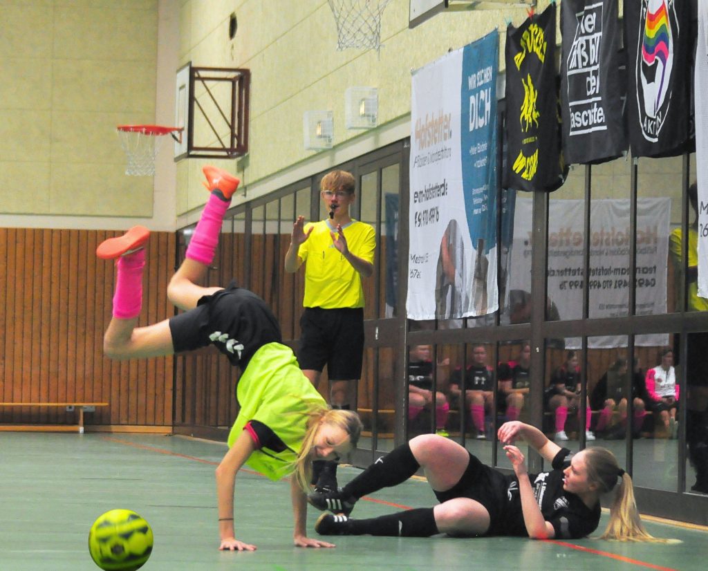 Zwei Fußballspielerinnen und ein Schiedsrichter während des Spiels.