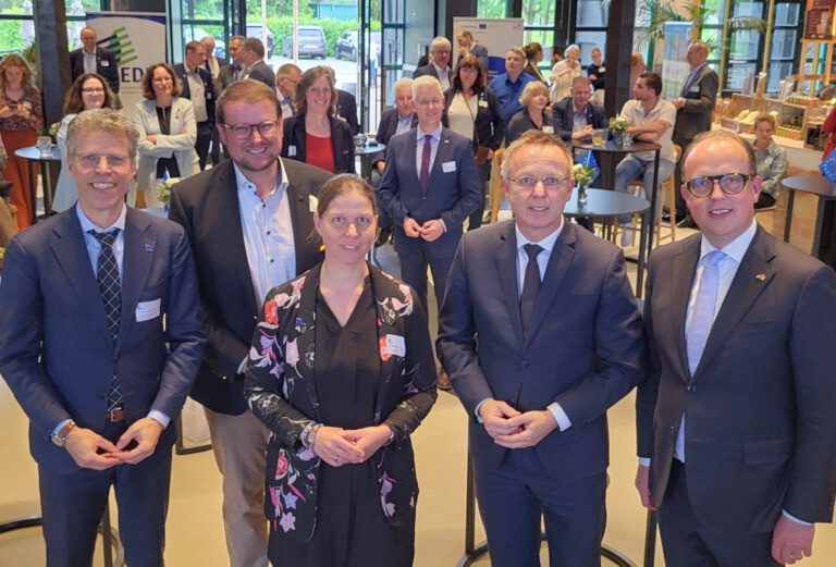 Im Hintergrund Publikum. Im Vordergrund fünf Menschen.